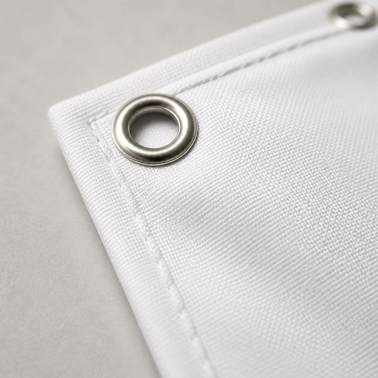 Close-up of white hem and reinforced metal grommet